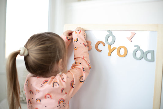 gale tots aesthetic magnetic letters and little girl placing the alphabet magnets on a whiteboard
