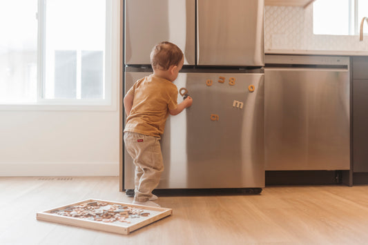 toddler playing with magnetic letters on the fridge