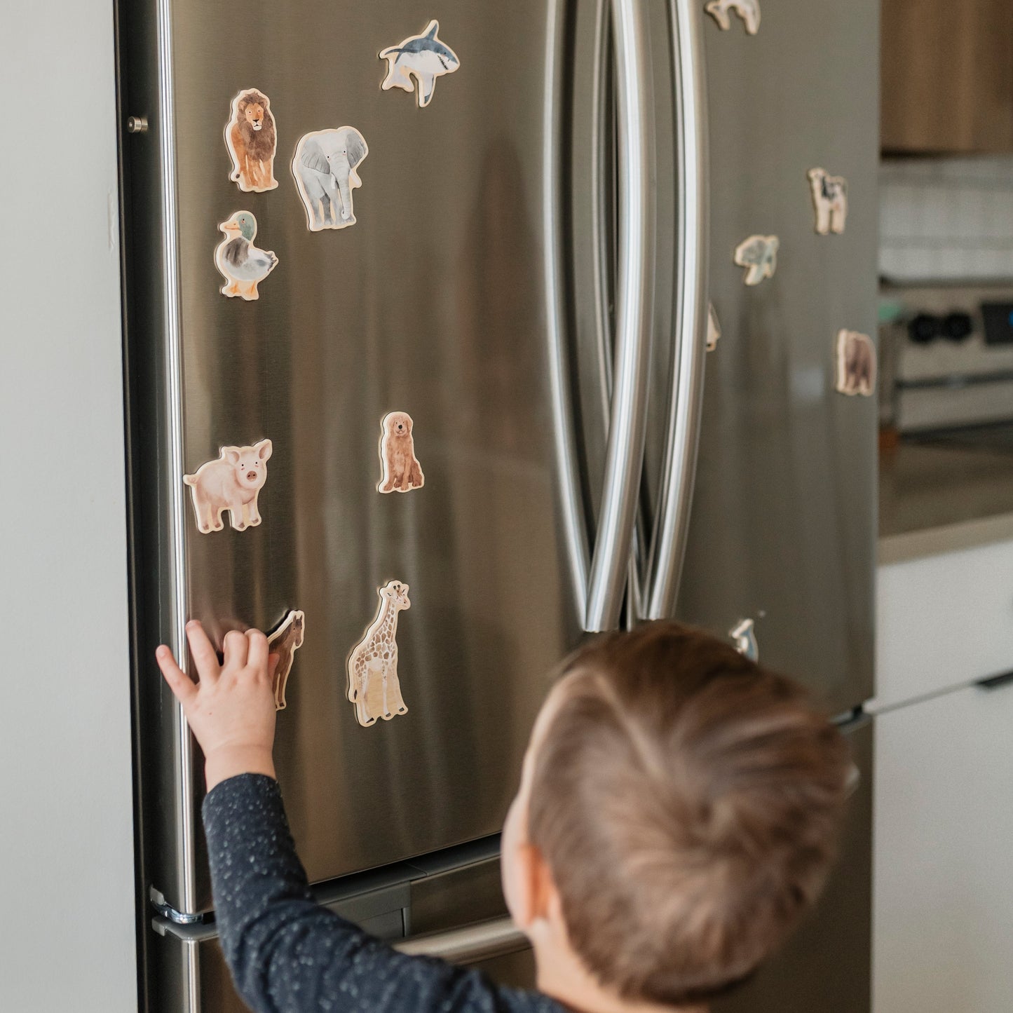 Child interacting with refrigerator magnets on a kitchen door